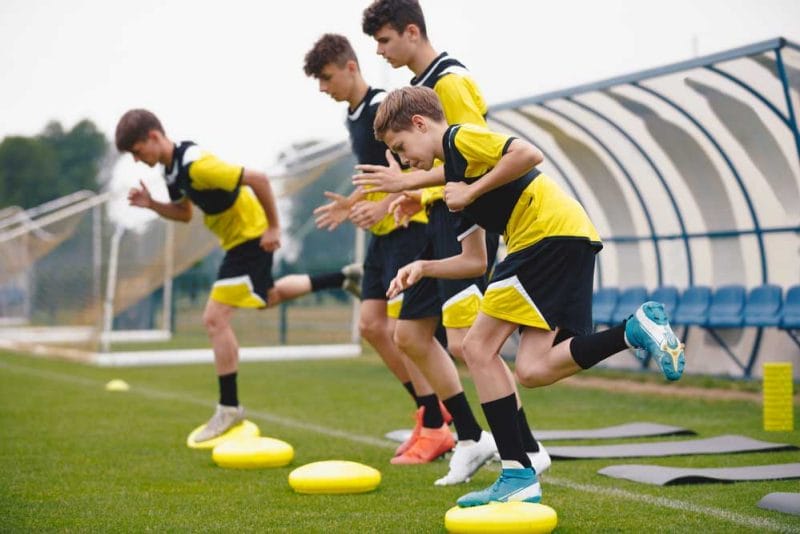 Football Balance Training. Youths on Stability Sports Training on Balance Cushions. Young Soccer Players Improving Core Strength, Balance and Stability Skills. Grass Football Field. Coaching Soccer