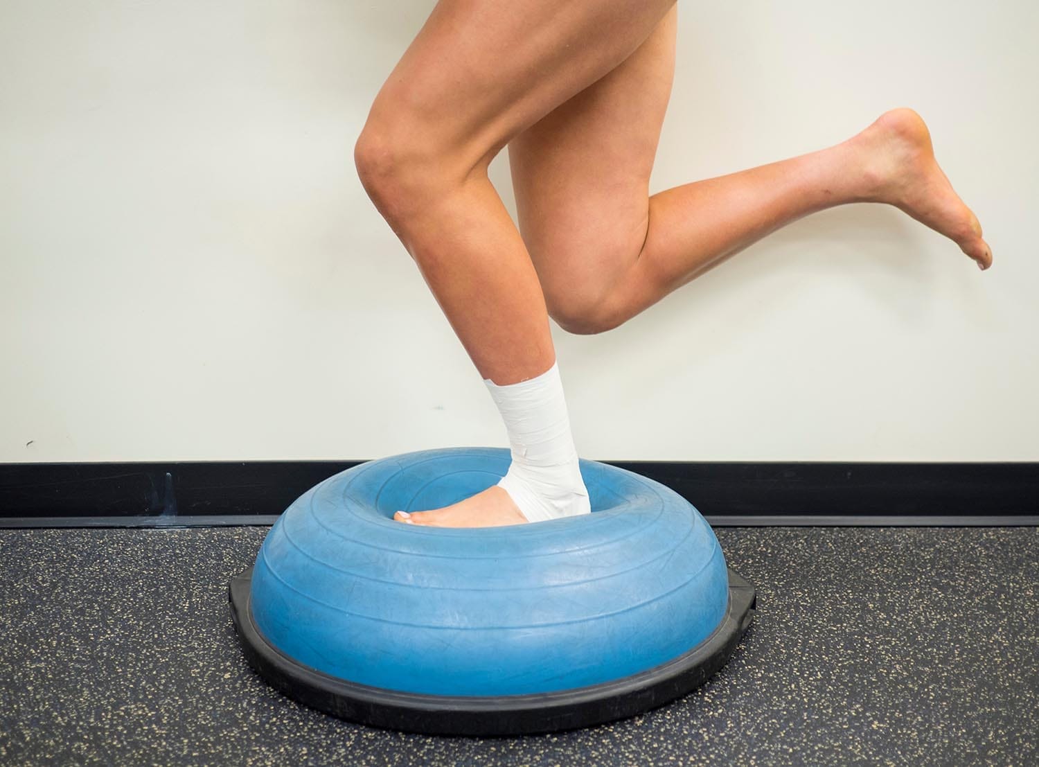 Athlete with a sprained ankle doing strengthening and balance exercises on a bosu ball