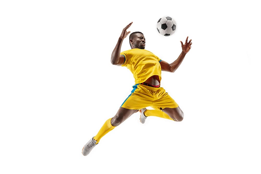 Professional african american football soccer player in motion isolated on white studio background. Fit jumping man in action, jump, movement at game.