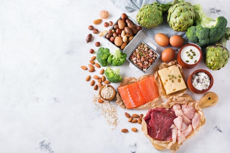 Assortment of healthy protein source and body building food. Meat beef salmon chicken breast eggs dairy products cheese yogurt beans artichokes broccoli nuts oat meal. Copy space background, top view