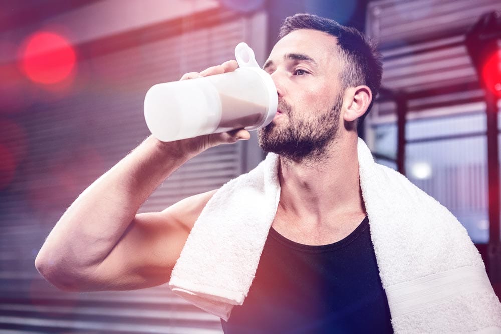 Muscular man drinking protein shake at crossfit gym