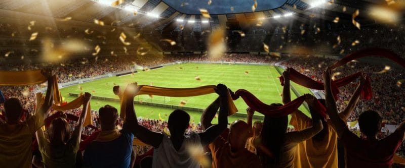 Support. Back view of football, soccer fans cheering their team with colorful scarfs at crowded stadium at evening time. Concept of sport, cup, world, team, event, competition