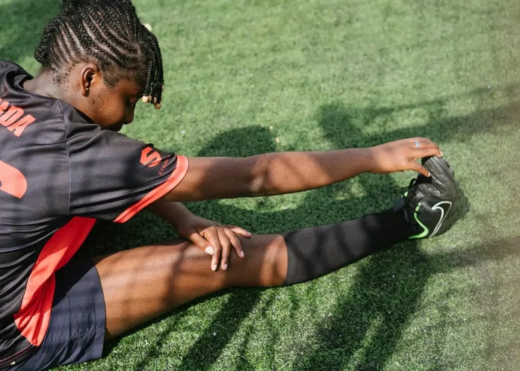 a young female footballer sat down doing stretches