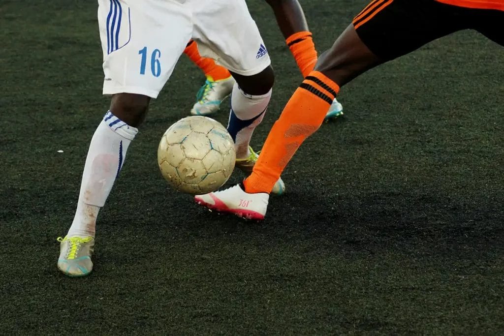 close up photo of two footballers legs challenging for a ball